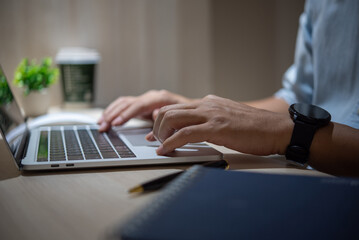Hands typing on a laptop keyboard while wearing a smartwatch..