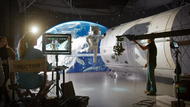 Female Directing a Movie Sequence with an Astronaut in Open Space. Studio with Virtual Production Screen Showing CGI Imagery with Planet Earth and a Practical Effect Mock Up of a Satellite
