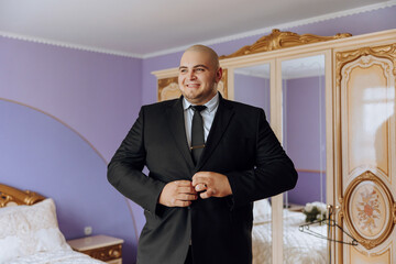 young smiling man buttoning up his jacket in the morning before the wedding. close-up of a man in a...