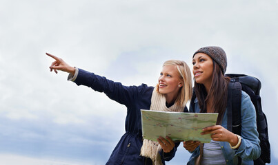 Woman, friends and pointing with map for direction or location on hiking adventure together in...