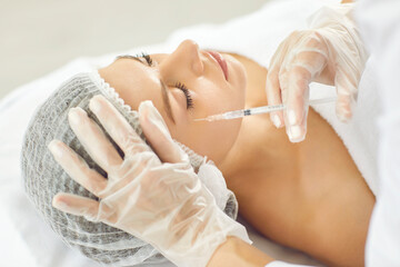 Woman receives dermal face injection. Doctor at cosmetological clinic gives beauty injection to...