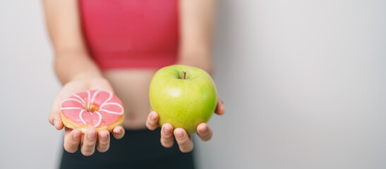 woman hand hold green Apple and donut, female fitness choose between fruit is Healthy and sweet is Unhealthy junk food. Dieting control, Weight loss, Obesity, eating lifestyle and nutrition concept