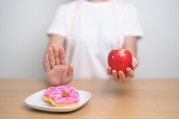 woman hand hold red Apple and reject donut, female fitness choose between fruit is Healthy and...