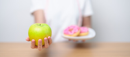 woman hand hold green Apple and donut, female fitness choose between fruit is Healthy and sweet is...