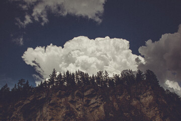 A cumulus cloud hovers above a treecovered mountain in the natural landscape