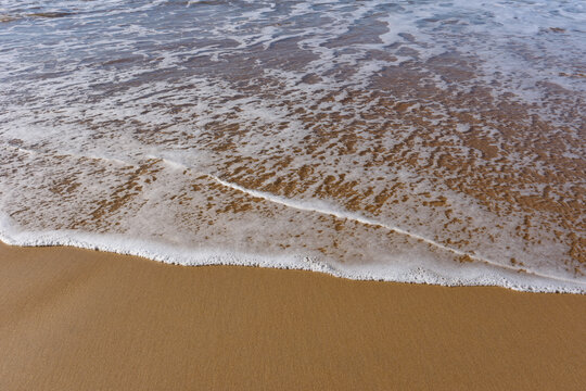 Espuma de mar  sobre la arena mojada en la orilla de una playa. 