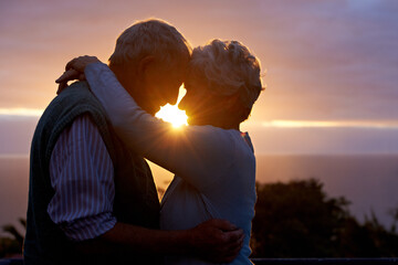Sunset, senior couple and embrace outdoor, care and bonding for connection together in nature. Man, woman and touch forehead for love, romance and hug for commitment to relationship in retirement
