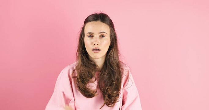 Brunette indignant woman showing blah blah blah gesture with hands isolated on studio pink background. Empty promises, blah concept. Lier, not interested. Annoyed girl making bla bla bla hand gesture
