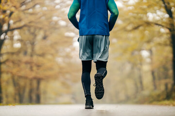 Rear view of an unrecognizable sportsman running in nature.