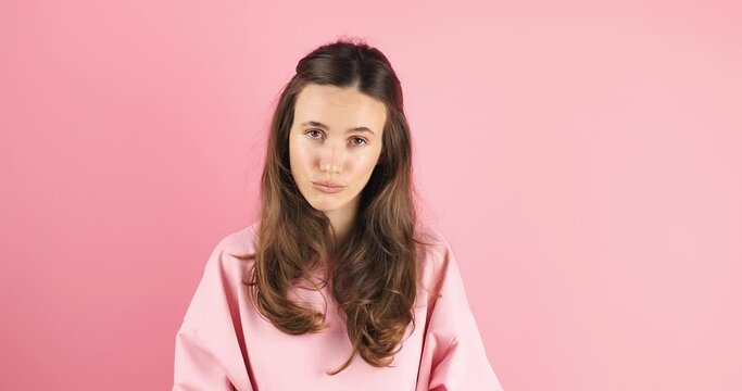Brunette woman threatens with a fist is isolated on pink background, shows fist has annoyed face expression going to revenge or threaten someone makes serious look. I will show you who is boss.