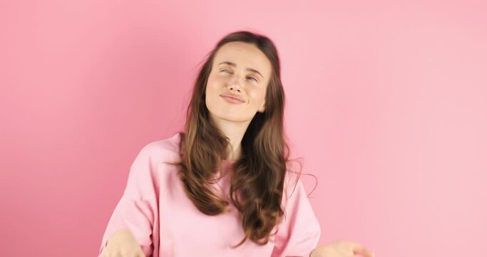 Young pathos woman pointing cheerfully while giving her imaginary money, in front of a pink background. The concept of pouring money without thinking. It makes it rain by throwing money into the air.