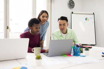 Diverse colleagues discussing project in bright office