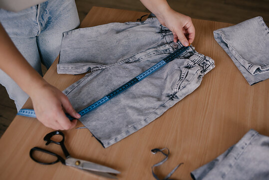 Woman seamstress cut and repair old jeans. Denim Upcycling Ideas. Reusing Old Jeans