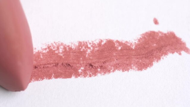Close up lipstick in peach fuzz color making a stroke on a white background. Cosmetic lip gloss, lipstick smudge, smear, stroke. Swatch of lip gloss on a white background.