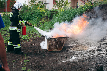 A firefighter is extinguishing a blazing fire with a fire extinguisher