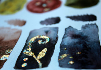 Photo of watercolor stains and gold leaf. Artist's desk.
