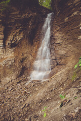 A beautiful waterfall cascades over a rocky cliff in a lush forest setting