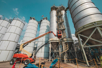 Male industry working at high in a boom liftinspection tank silo