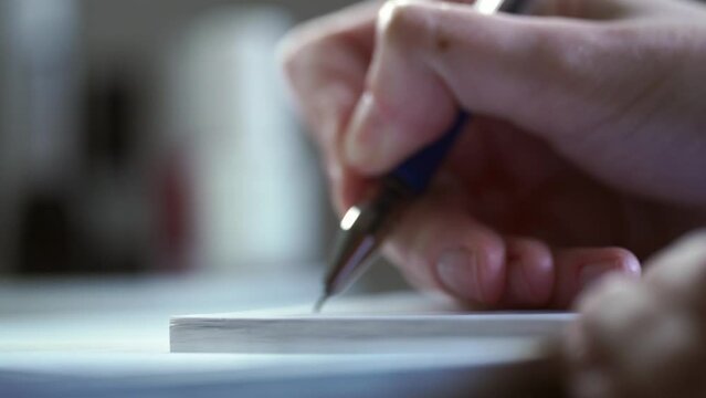 A man signs with a ballpoint pen on a white sheet of paper. Important notes. Office work. Woman hands writing on a piece of paper. Writing essay or letters. Doing homework.