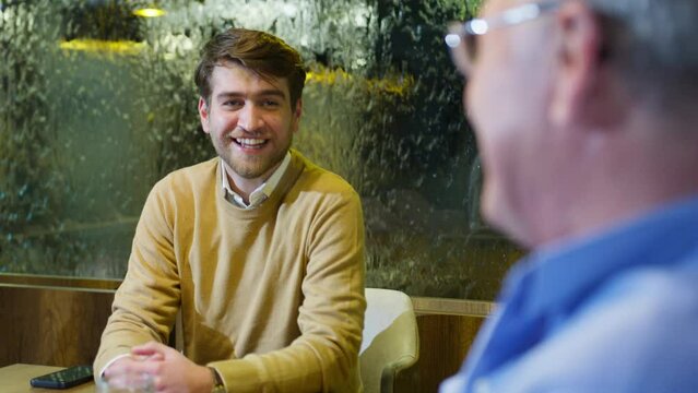 Young Caucasian Man Similing While Having a Conversation with His Father