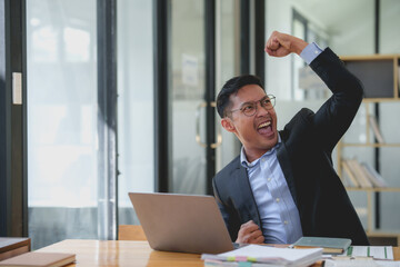 Excited asian businessman celebrating success at work. Achievement and business victory concept.