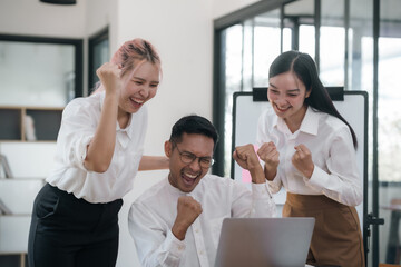 Enthusiastic Asian business team celebrating a successful project in office. Group achievement and teamwork concept.