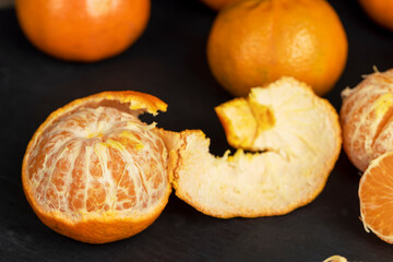 a large number of orange citrus fruits on a black slate surface