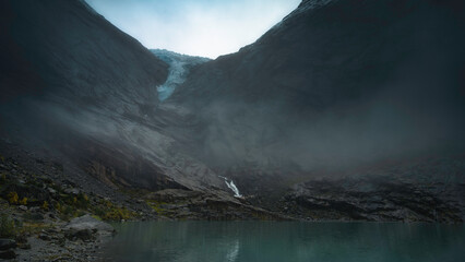 Norwegian mountain landscape, cloudy, with a lake, with the tongue of the Briksdalsbreen glacier in...