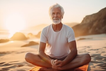 Fototapeta na wymiar Portrait of a senior man meditating on the beach at sunset