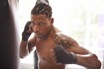 Boxing, portrait and black man with punch in gym for fitness challenge, fight and competition training. Power, muscle and serious face of champion boxer at workout with confidence in sports club.