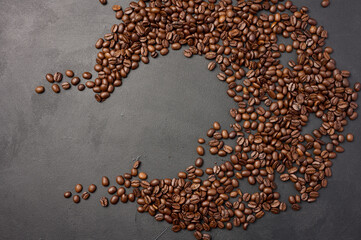 Scattered roasted coffee beans on black background, top view