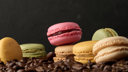 Stack of multi-colored macarons on a background of coffee beans, black background