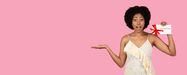 Excited young African American woman presenting a gift voucher with a red ribbon