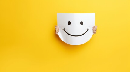 Person holding paper mask with yellow smiley face emoticon - obrazy, fototapety, plakaty
