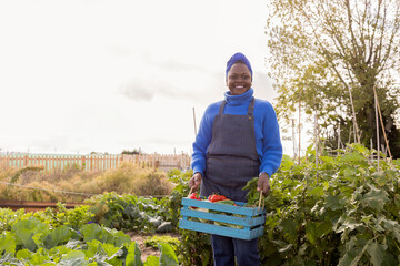 African mature woman in the garden carrying a basket with organic vegetables