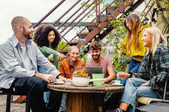 Diverse group of friends sharing ideas over coffee on a rooftop garden - Blending work and leisure in an urban setting