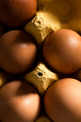 Close up view of brown eggs in yellow paper box
