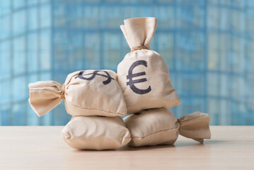 Money bags with euro symbol on background of modern city in defocus - 741465838