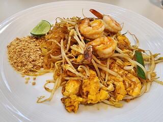 Pad Thai - Popular Thai food - Fried noodle Thai style with prawns : noodles made from rice, spices, egg, chives leaves, fresh shrimp, stir-fried with sauce and bean sprouts, served with peanuts- lime