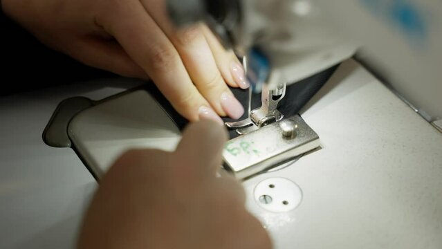 Enlarged image of seamstress sewing fabric on sewing machine.