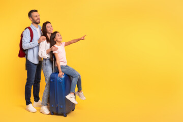 Smiling family showing free space for travel deals, yellow background