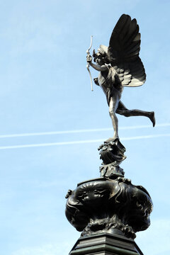 Statue of Eros the god of Love firing his bow.  Vapour trails from an airplane can be seen in the background.