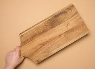 Female hand holding a rectangular wooden cutting board kitchen board