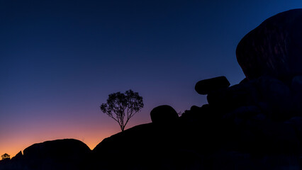 Devil's marbles, silhouette of a tree against the night sky, Australia