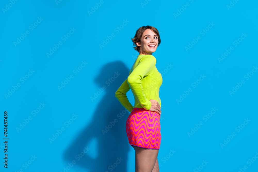 Sticker Photo of glamour outfit young lady in green shirt and pink mini skirt looking novelty clothes shopping isolated on blue color background