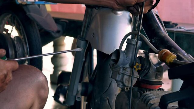 Motorcycle mechanic's hands stained with engine oil are using a screwdriver to repair a motorcycle.4k video