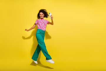 Fototapeta na wymiar Full length portrait of carefree nice portrait jumping hold smart phone empty space ad isolated on yellow color background