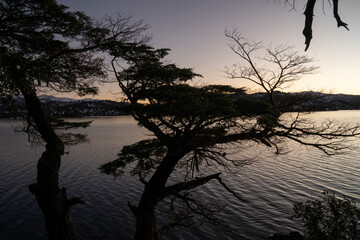 Magical view of the lake, mountains and forest trees at sunset. 