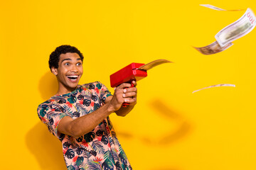 Photo of young wealthy man in t shirt shooting banknotes money gun feeling spend his all income...