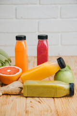 Fruit and vegetable smoothies in transparent plastic bottles. Green, orange, red smoothies on a wooden table. The concept of healthy eating. Front view
